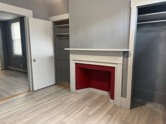 a view of an empty room with wooden floor and a fireplace