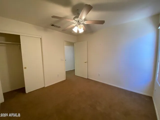 an empty room with a chandelier fan and windows