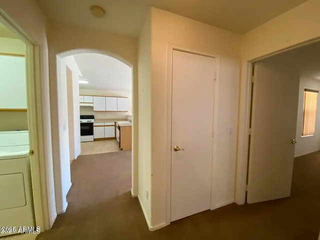 a view of a livingroom and a hallway to a livingroom with furniture