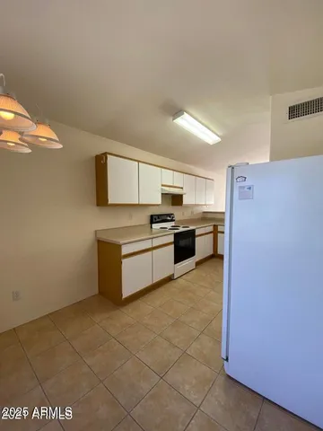 a kitchen with granite countertop a refrigerator and a stove top oven