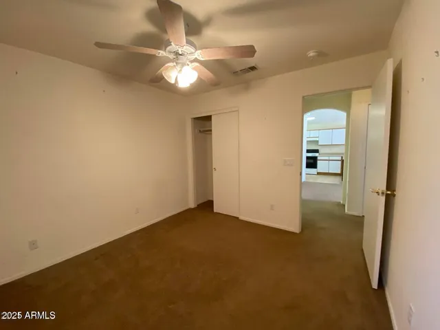 an empty room with chandelier fan and windows
