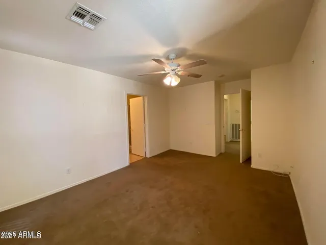 an empty room with a chandelier fan and windows