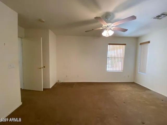an empty room with windows and fan