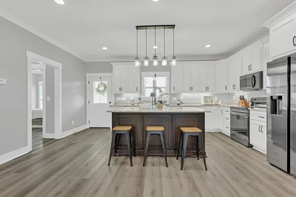 a kitchen with stainless steel appliances a dining table chairs stove refrigerator and cabinets