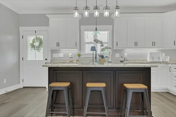 a kitchen with stainless steel appliances a dining table chairs and white cabinets