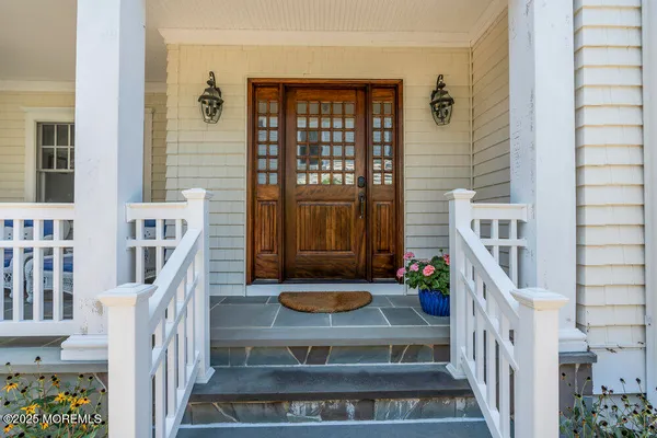 a living room with couches chandelier and a dining table with wooden floor