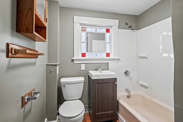 a bathroom with a toilet sink vanity tub and mirror