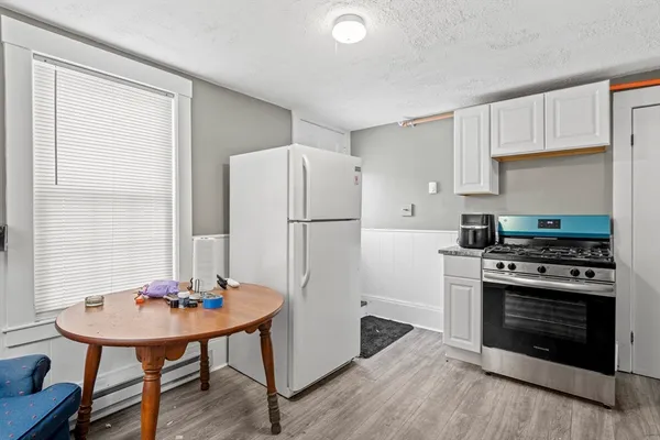 a kitchen with stainless steel appliances a stove a refrigerator and a dining table with white cabinets