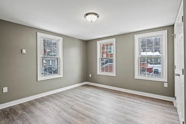 a view of an empty room with a window and wooden floor