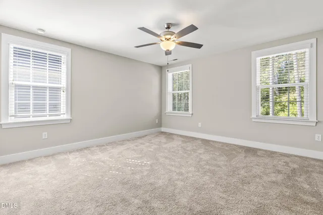 an empty room with window and ceiling fan