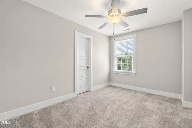 an empty room with windows and ceiling fan