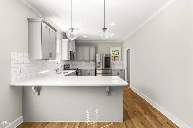 a view of a kitchen with a sink and dishwasher a refrigerator with wooden floor