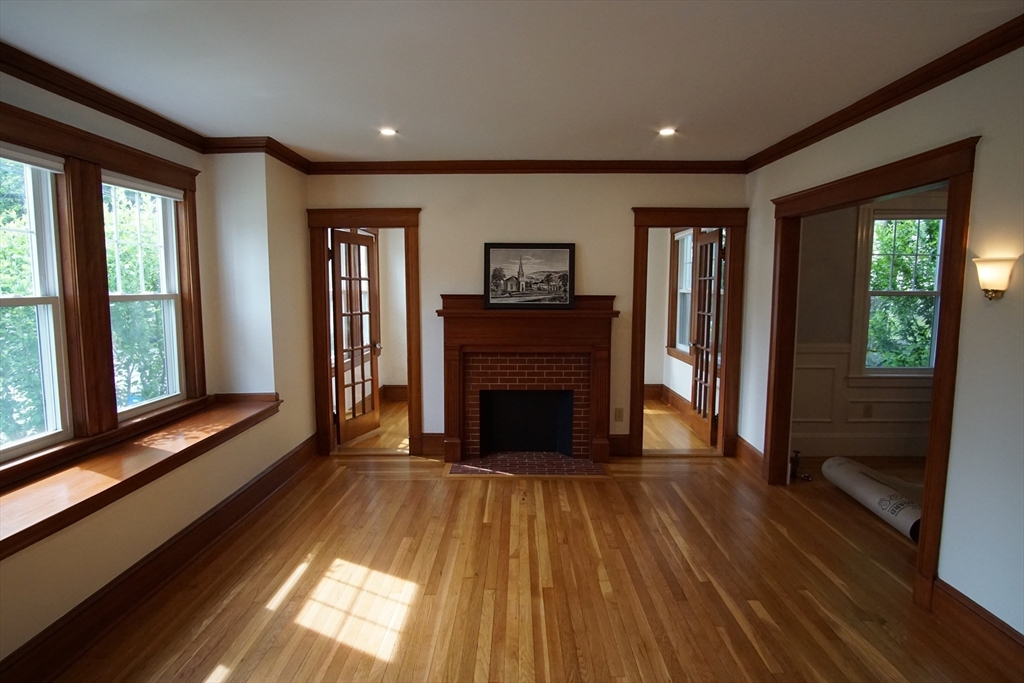 754 Massachusetts Avenue, Unit 1 Lexington, MA 02421 - Photo 2 of 17 a view of a hallway with wooden floor fireplace and windows