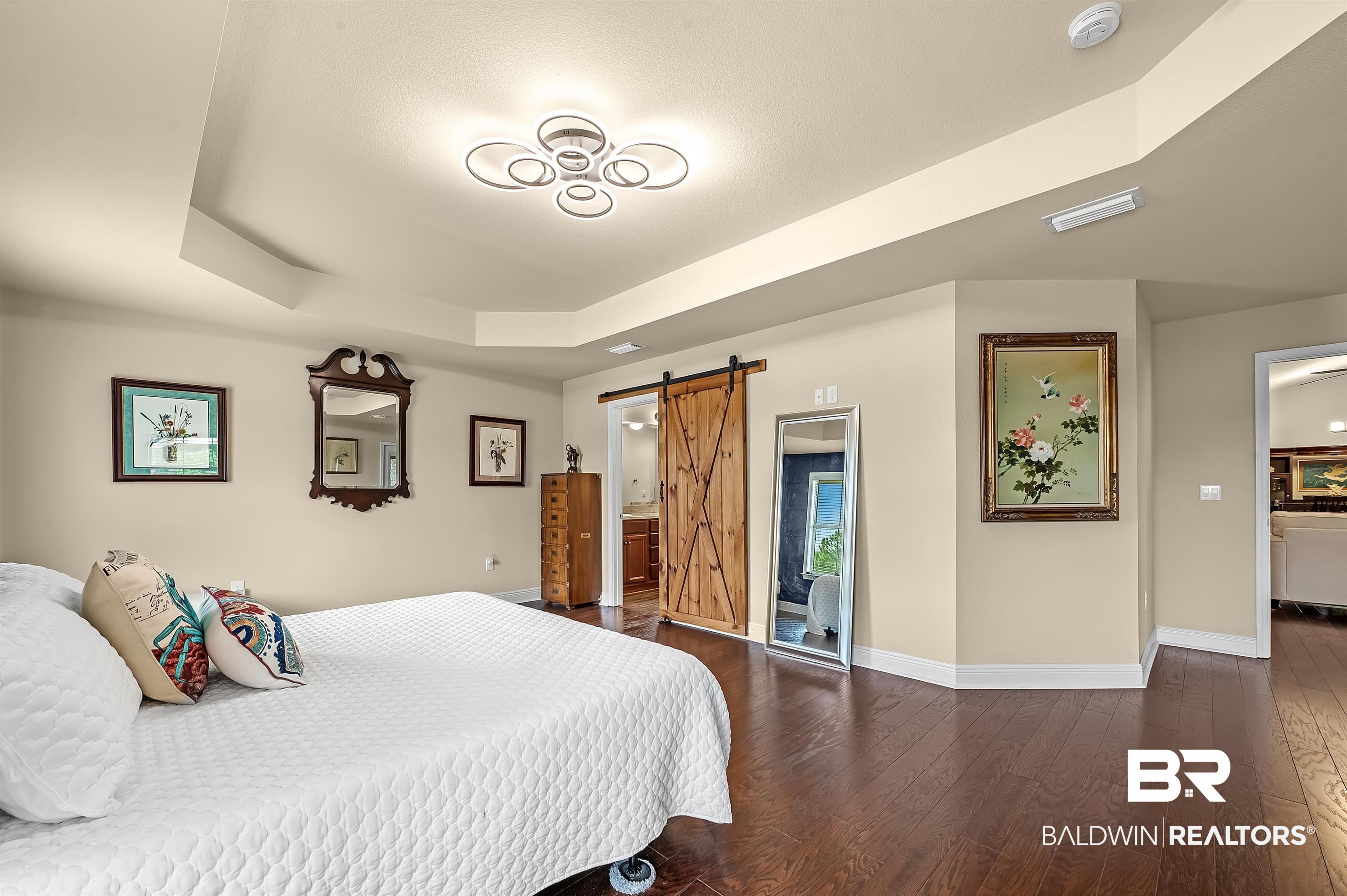 8896 Allay Lane Foley, AL 36535 - Photo 41 of 57 Bedroom with connected bathroom, a raised ceiling, dark hardwood / wood-style flooring, and a barn door
