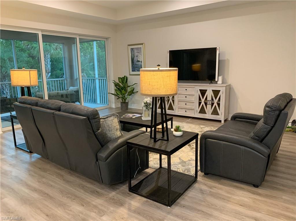 208 Indies Drive East, Unit 202 Naples, FL 34114 - Photo 14 of 48 a living room with furniture a flat screen tv and a large window
