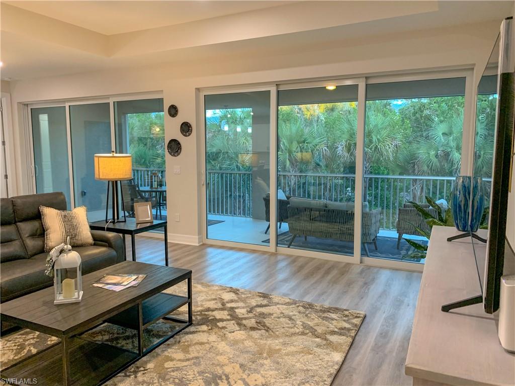 208 Indies Drive East, Unit 202 Naples, FL 34114 - Photo 15 of 48 a living room with furniture and a large window