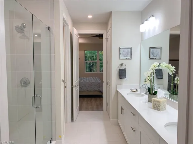 a spacious en suite bathroom with a double vanity sink a large mirror a shower and vanity