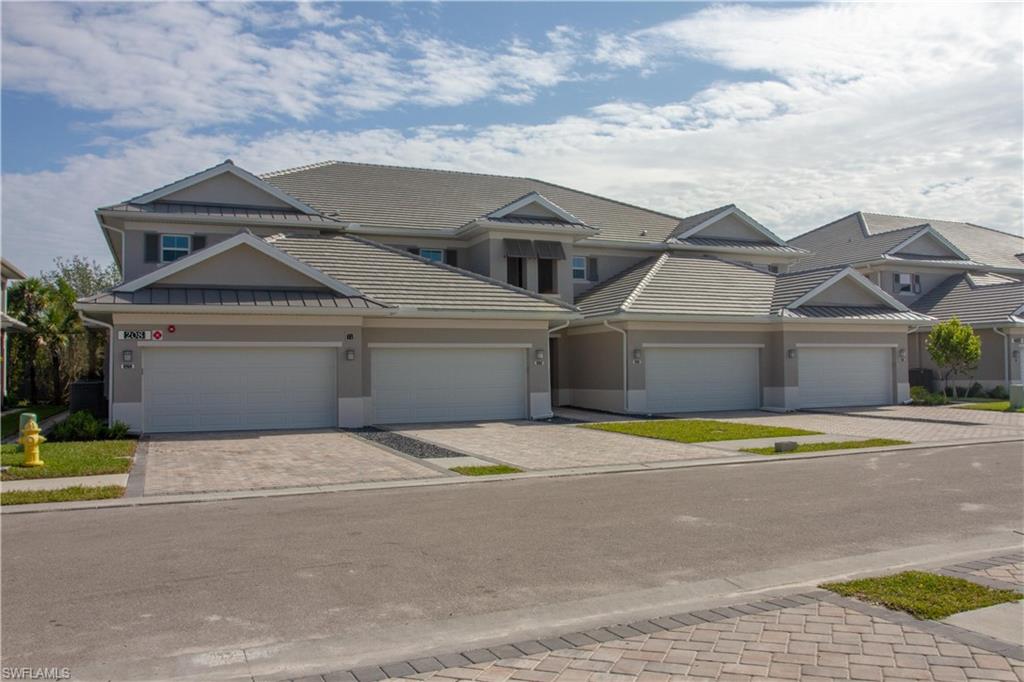 208 Indies Drive East, Unit 202 Naples, FL 34114 - Photo 2 of 48 a front view of a house with a yard and garage