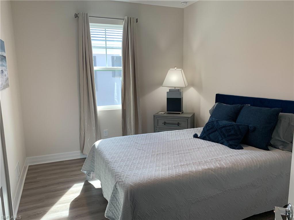 208 Indies Drive East, Unit 202 Naples, FL 34114 - Photo 27 of 48 a bedroom with a bed and a lamp