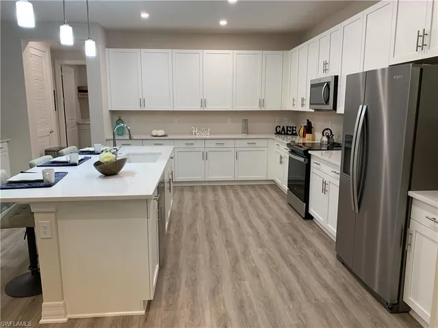 a kitchen with a sink a counter top space stainless steel appliances and cabinets