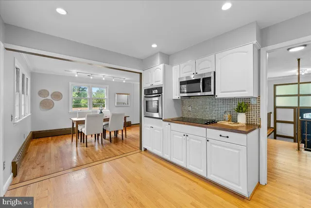 a large kitchen with cabinets chairs and wooden floor