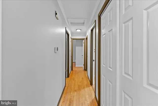 a view of a hallway with wooden floor and a bathroom