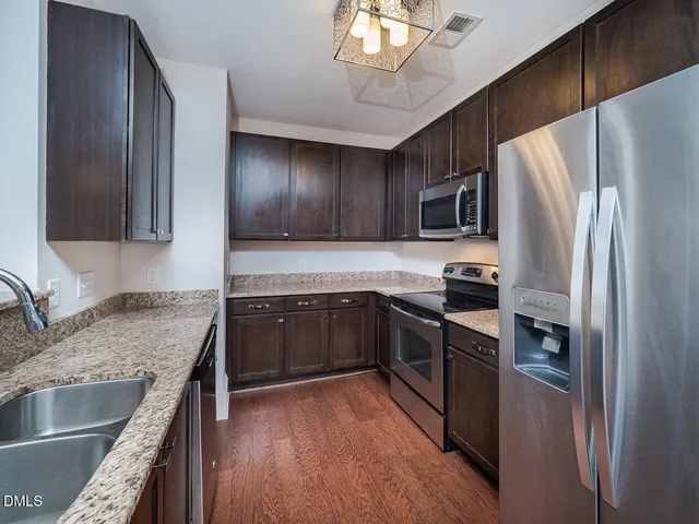 a kitchen with stainless steel appliances granite countertop a refrigerator a stove top oven a sink and dishwasher