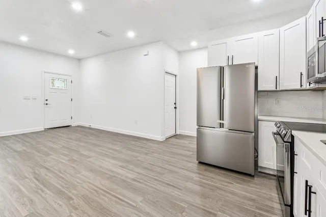 a kitchen with stainless steel appliances a refrigerator and a hard wood floor