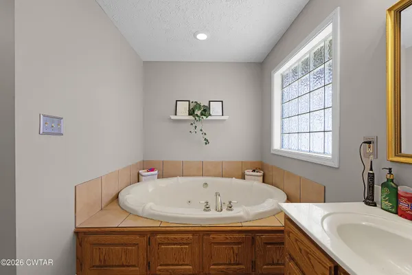 a bathroom with a granite countertop sink a bathtub and window