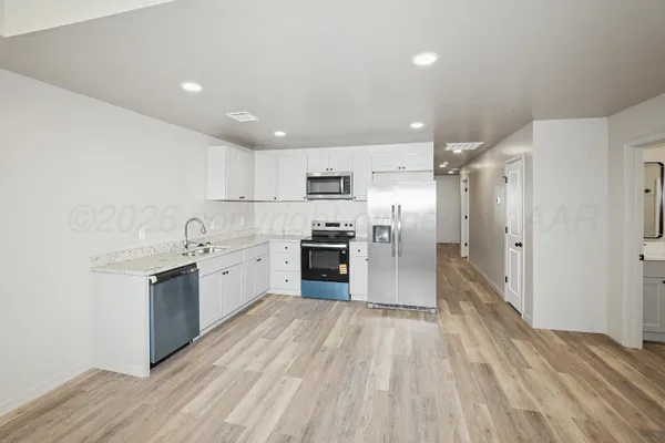 a large kitchen with granite countertop a large counter top stainless steel appliances and cabinets