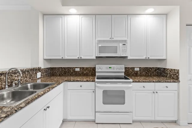 a kitchen with granite countertop white cabinets and white appliances