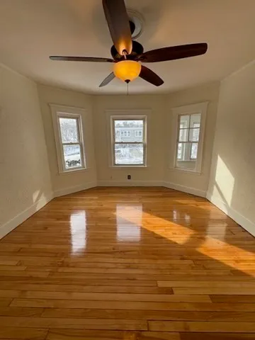 a view of empty room with window and ceiling fan
