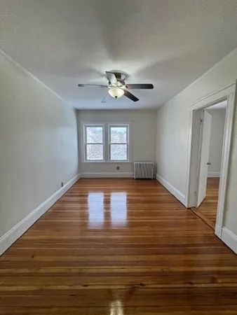 a view of empty room with wooden floor and fan