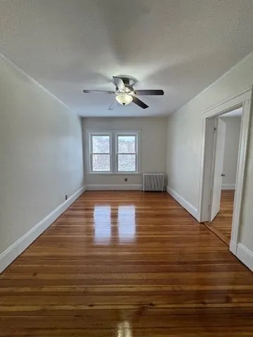 a view of empty room with wooden floor and fan