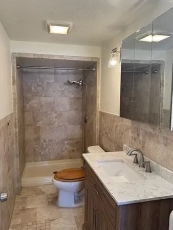 a bathroom with a granite countertop sink toilet a shower and a mirror
