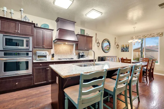 a kitchen with stainless steel appliances granite countertop a table chairs refrigerator and sink