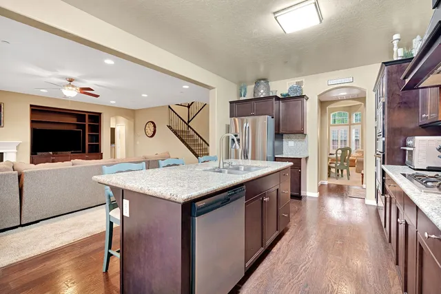 a kitchen with stainless steel appliances granite countertop a stove a refrigerator a sink dishwasher with wooden cabinets and floor