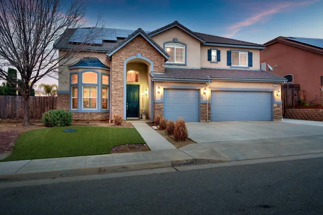 a front view of a house with garage and plants