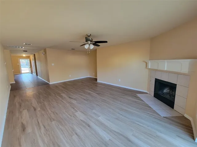an empty room with wooden floor fireplace and windows