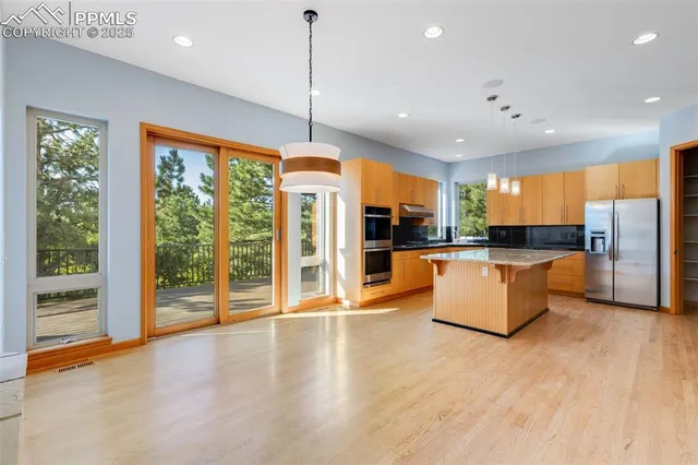 a large kitchen with stainless steel appliances kitchen island a large counter top and a wooden floors