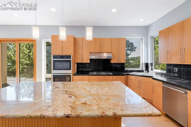 a large white kitchen with granite countertop a sink and cabinets