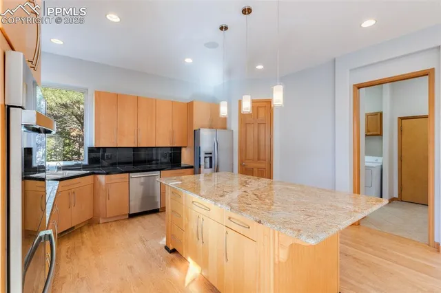 a kitchen with stainless steel appliances granite countertop a sink and a refrigerator