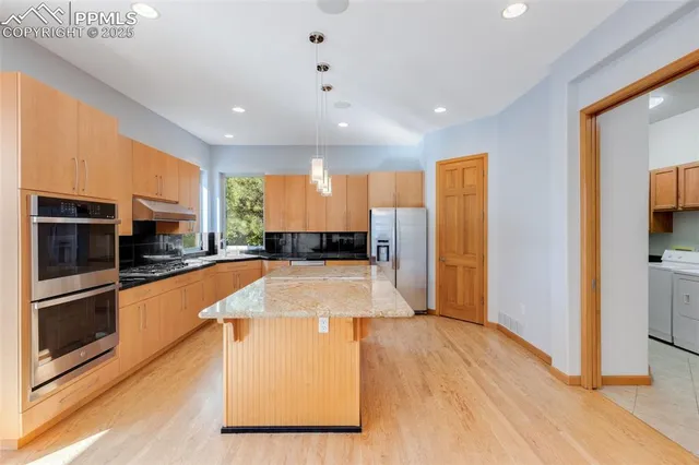 a large kitchen with stainless steel appliances granite countertop a large counter top a stove and a refrigerator