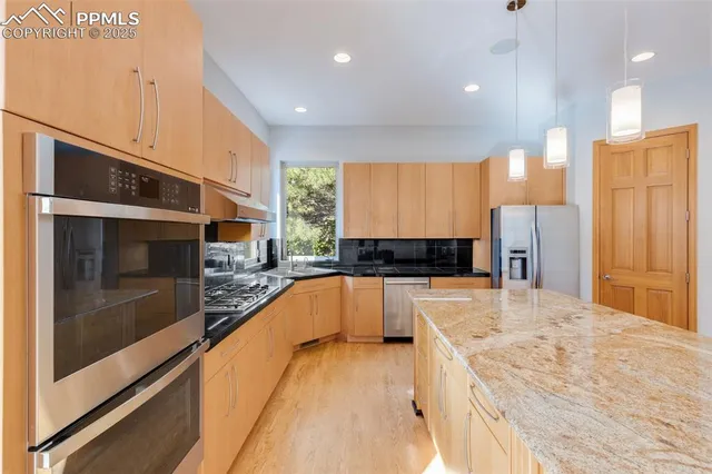 a large kitchen with stainless steel appliances kitchen island a large counter top and a refrigerator