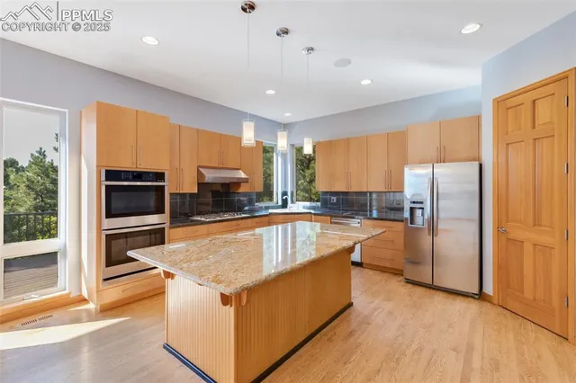 a kitchen with stainless steel appliances granite countertop a refrigerator a sink dishwasher a stove and a refrigerator with wooden floor