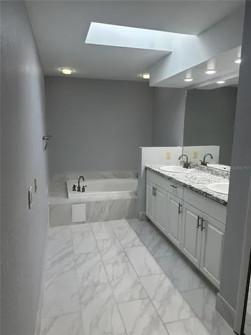 a bathroom with a bathtub sink vanity and mirror