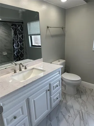 a bathroom with a granite countertop toilet sink and mirror