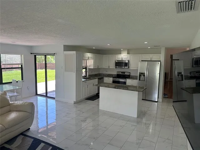 a kitchen with stainless steel appliances kitchen island granite countertop a refrigerator and microwave