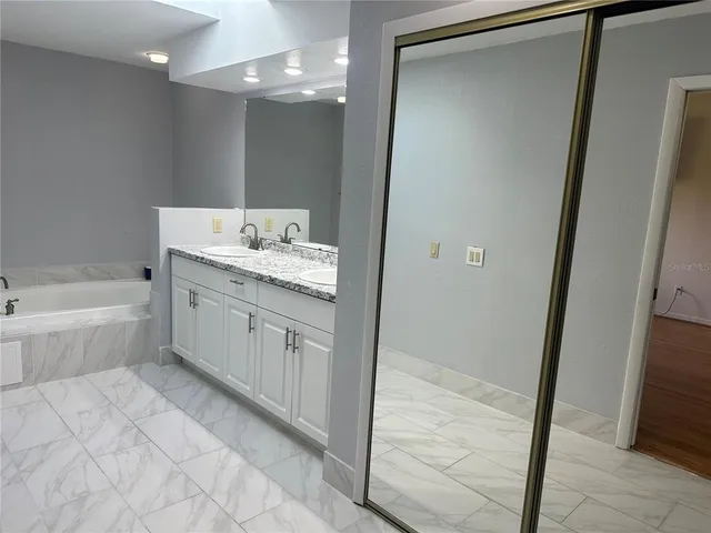 a bathroom with a bathtub sink vanity and a mirror