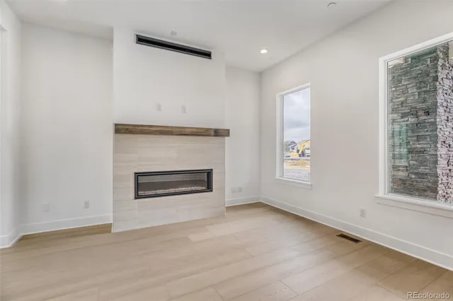 an empty room with windows and fireplace